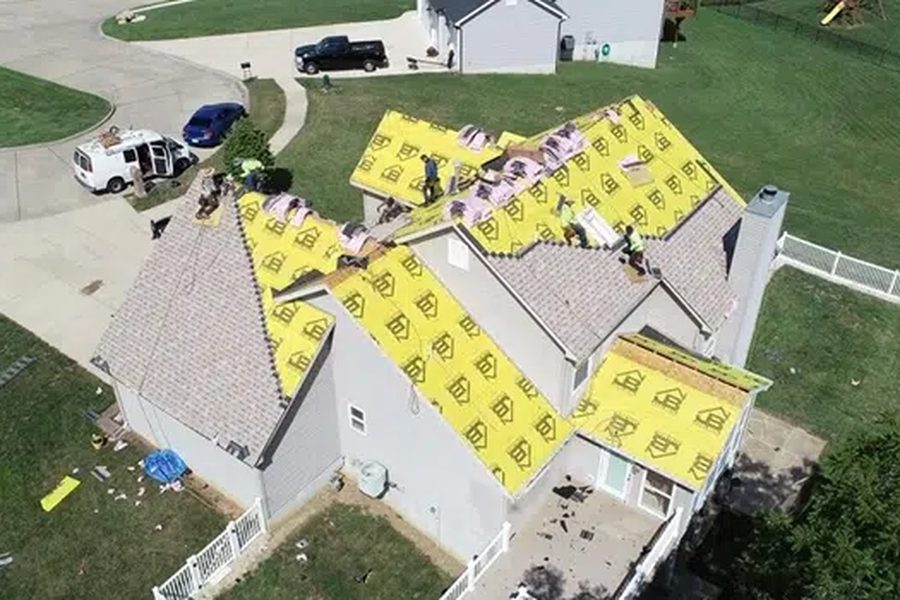 Roofing company crew installing asphalt shingles over yellow underlayment on an Indianapolis home